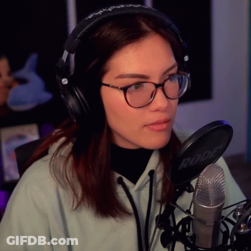 A Woman Wearing Glasses And Headphones Is Sitting In Front Of A Rode Microphone GIF