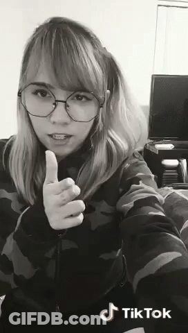 A Woman Wearing Glasses Is Giving A Thumbs Up Sign In A Black And White Photo . GIF