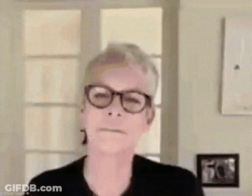 A Woman Wearing Glasses Is Making A Funny Face While Standing In Front Of A Window . GIF