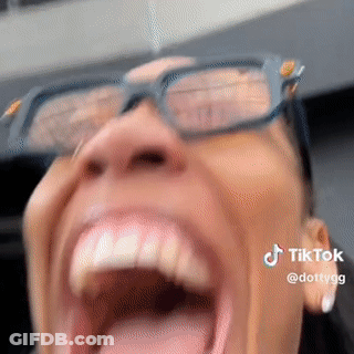 A Woman Wearing Glasses Is Screaming With Her Mouth Open . GIF