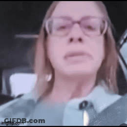 A Woman Wearing Glasses Is Sitting In A Car And Looking At The Camera . GIF