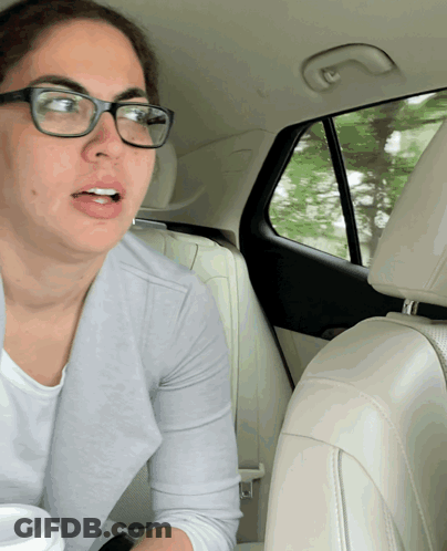 A Woman Wearing Glasses Is Sitting In A Car GIF