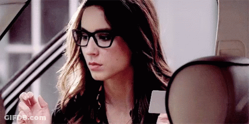 A Woman Wearing Glasses Is Sitting In A Car . GIF
