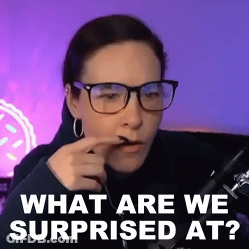 A Woman Wearing Glasses Is Sitting In Front Of A Microphone And Making A Surprised Face . GIF