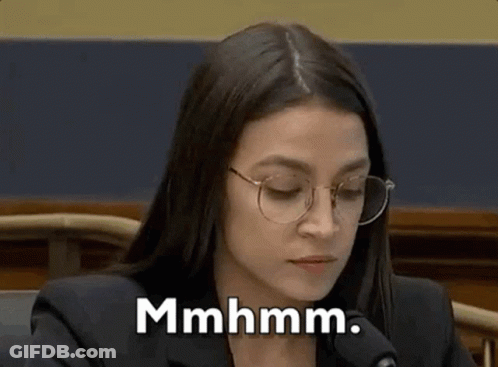 A Woman Wearing Glasses Is Sitting In Front Of A Microphone . GIF
