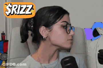 A Woman Wearing Glasses Is Sitting In Front Of A Microphone With A Sticker That Says $Rizz On It GIF