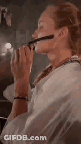 A Woman Wearing Glasses Is Sitting On A Couch And Looking Through A Pair Of Binoculars . GIF