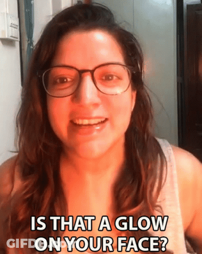 A Woman Wearing Glasses Is Smiling And Asking If There Is A Glow On Her Face GIF