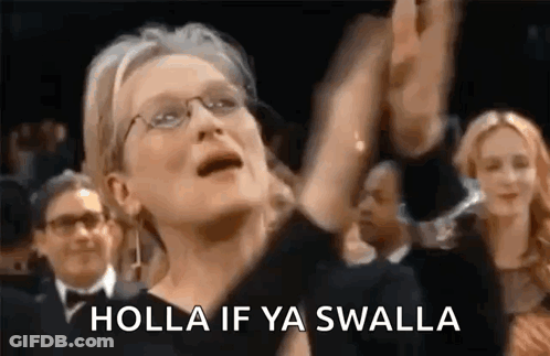 A Woman Wearing Glasses Is Standing In A Crowd With Her Arms In The Air And Says Holla If Ya Swalla . GIF