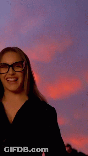 A Woman Wearing Glasses Is Sticking Out Her Tongue . GIF