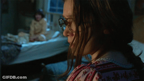 A Woman Wearing Glasses Looks At Something In The Dark GIF
