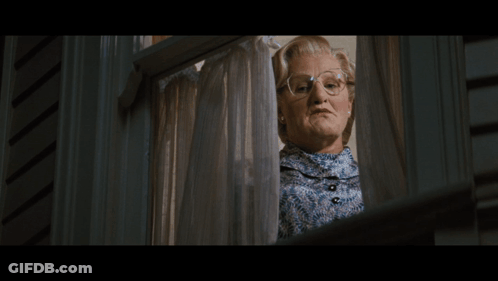 A Woman Wearing Glasses Looks Out A Window GIF