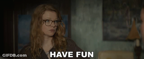 A Woman Wearing Glasses Says " Have Fun " In A Dark Room GIF