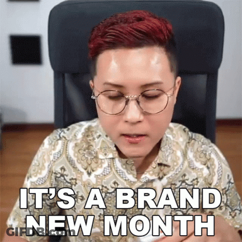 A Woman Wearing Glasses Says It 'S A Brand New Month While Sitting In A Chair GIF