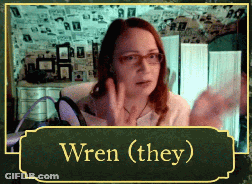 A Woman Wearing Glasses Talks Into A Microphone With The Words Wren ( They ) Above Her GIF