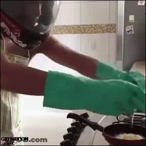 A Woman Wearing Green Gloves Is Cooking On A Stove .. GIF