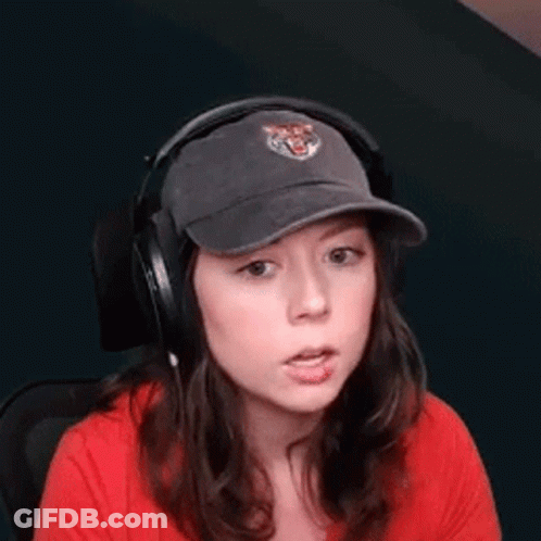 A Woman Wearing Headphones And A Baseball Cap Is Sitting In A Chair . GIF