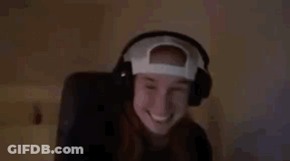 A Woman Wearing Headphones And A Baseball Cap Is Smiling And Waving . GIF