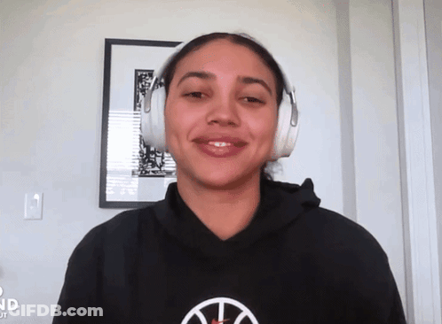 A Woman Wearing Headphones And A Black Hoodie With A Basketball Logo GIF