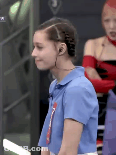 A Woman Wearing Headphones And A Blue Shirt With The Word Overdo On The Sleeve GIF
