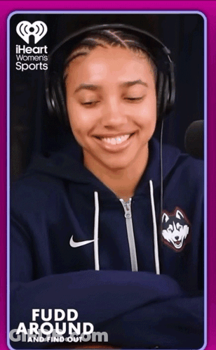 A Woman Wearing Headphones And A Blue Sweatshirt With A Husky On It Is On A Iheart Women 'S Sports Ad GIF