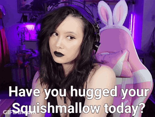 A Woman Wearing Headphones And A Bunny Headband Is Asking If She Hugged Her Squishmallow Today GIF