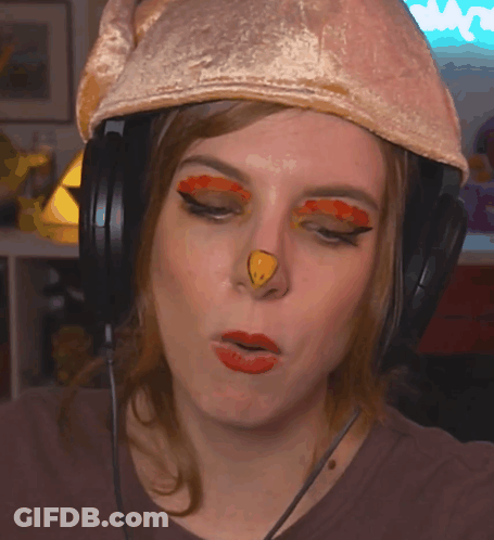 A Woman Wearing Headphones And A Chicken Hat Has A Yellow Nose GIF