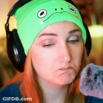 A Woman Wearing Headphones And A Green Hat With A Face On It GIF