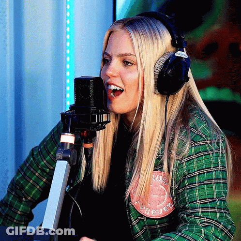 A Woman Wearing Headphones And A Green Plaid Shirt Has A Patch On Her Shirt That Says Forever GIF