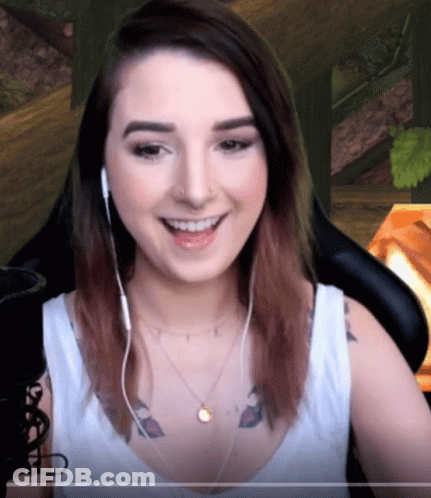 A Woman Wearing Headphones And A Necklace Smiles GIF