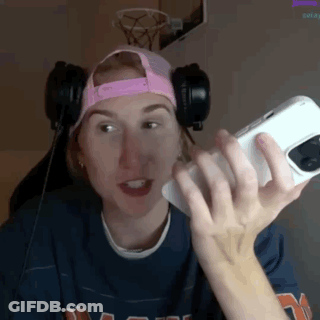 A Woman Wearing Headphones And A Pink Hat Is Holding A Phone GIF