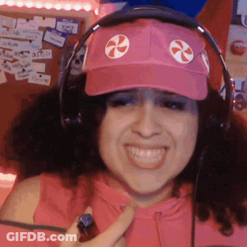 A Woman Wearing Headphones And A Pink Hat With A Candy Cane On It GIF