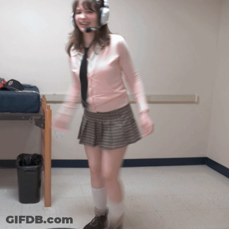 A Woman Wearing Headphones And A Pink Sweater Is Standing In A Room GIF