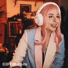 A Woman Wearing Headphones And A Pink Wig Is Smiling . GIF