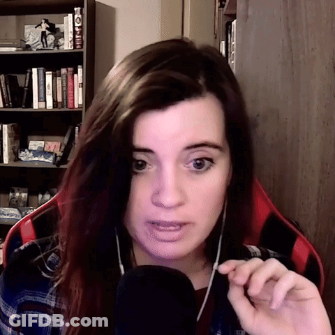 A Woman Wearing Headphones And A Plaid Shirt Is Talking Into A Microphone In Front Of A Bookshelf GIF