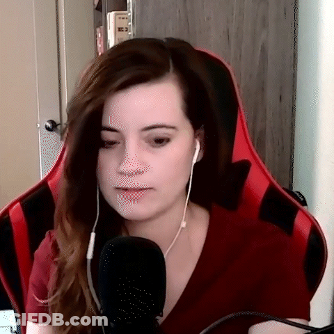 A Woman Wearing Headphones And A Red Shirt Is Sitting In A Red Chair . GIF