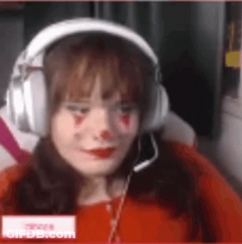 A Woman Wearing Headphones And A Red Shirt Is Sitting In Front Of A Computer Screen . GIF