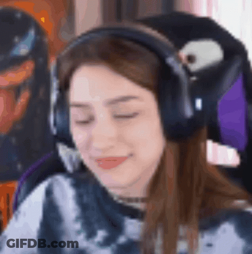 A Woman Wearing Headphones And A Tie Dye Shirt Is Sitting In A Chair With Her Eyes Closed . GIF