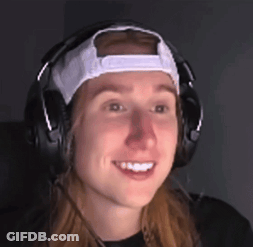 A Woman Wearing Headphones And A White Hat Smiles For The Camera GIF
