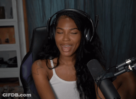 A Woman Wearing Headphones And A White Tank Top Smiles While Sitting In Front Of A Microphone GIF