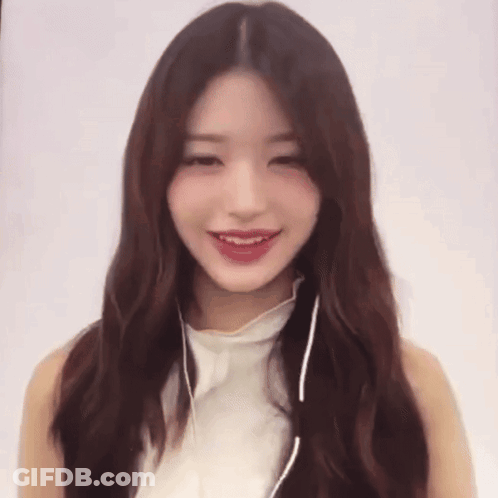 A Woman Wearing Headphones And A White Top Smiles GIF