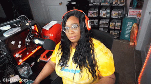 A Woman Wearing Headphones And A Yellow Shirt That Says Matterfinger Is Sitting In Front Of A Microphone GIF