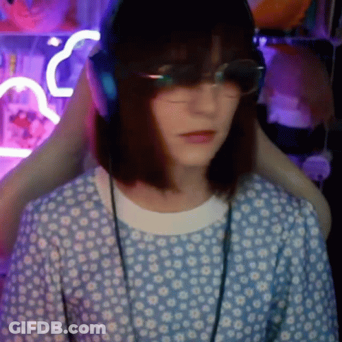 A Woman Wearing Headphones And Glasses Is Sitting In A Chair In A Room . GIF