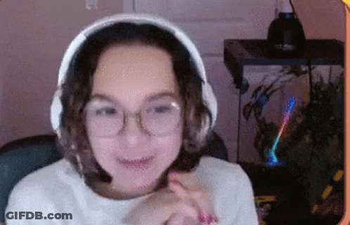 A Woman Wearing Headphones And Glasses Is Sitting In Front Of A Computer Monitor . GIF
