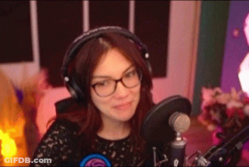 A Woman Wearing Headphones And Glasses Is Sitting In Front Of A Microphone In A Recording Studio . GIF