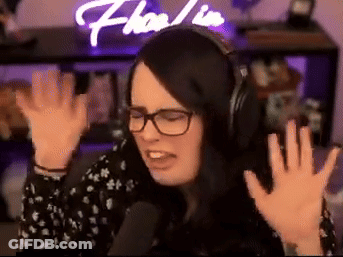 A Woman Wearing Headphones And Glasses Is Sitting In Front Of A Microphone . GIF