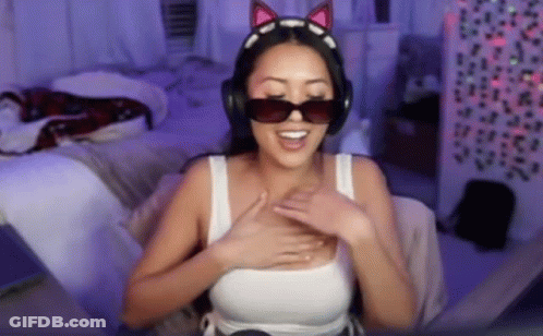 A Woman Wearing Headphones And Sunglasses Is Sitting On A Bed . GIF