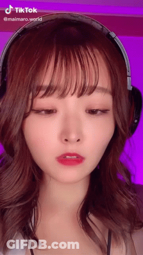 A Woman Wearing Headphones Has A Tiktok Sticker On Her Face GIF