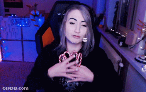 A Woman Wearing Headphones Is Holding A Candy Cane In Her Hand GIF