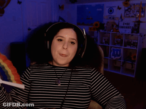 A Woman Wearing Headphones Is Holding A Rainbow Lollipop And Says I Have Tons Of Questions GIF